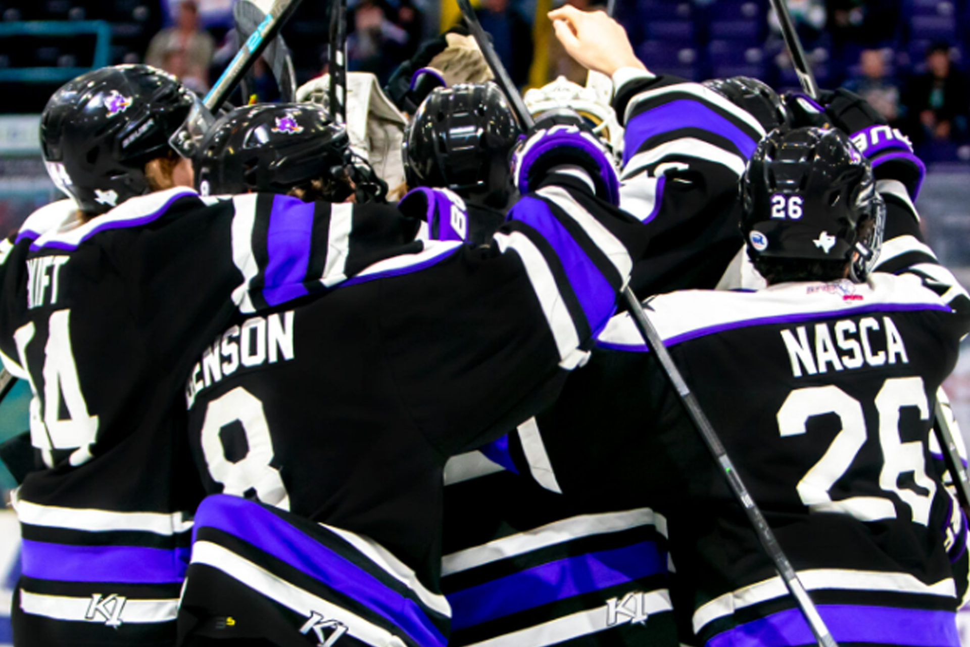 hockey players in black jerseys celebrating with arms around each other